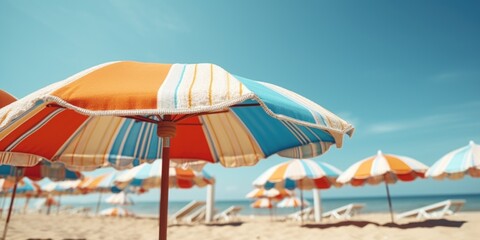 Colorful umbrellas lined up on a sandy beach near the ocean. Perfect for summer vacation or beach-themed designs