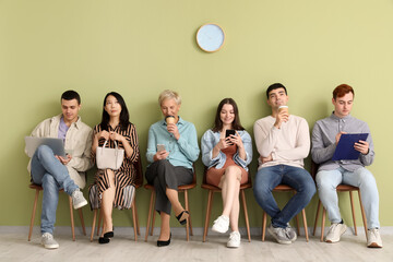 Applicants waiting for job interview near green wall in room