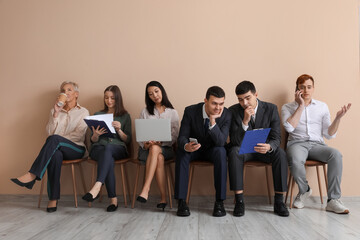 Applicants waiting for job interview near beige wall