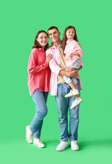 Fototapeta premium Little girl with her parents on green background
