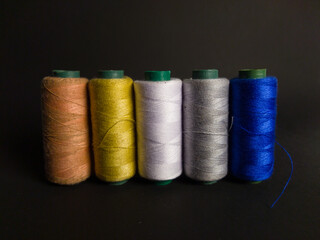 collection of sewing thread spools on black background