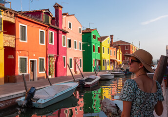 Rear view of tourist woman with hat watching scenic view of bright colorful houses on island of...