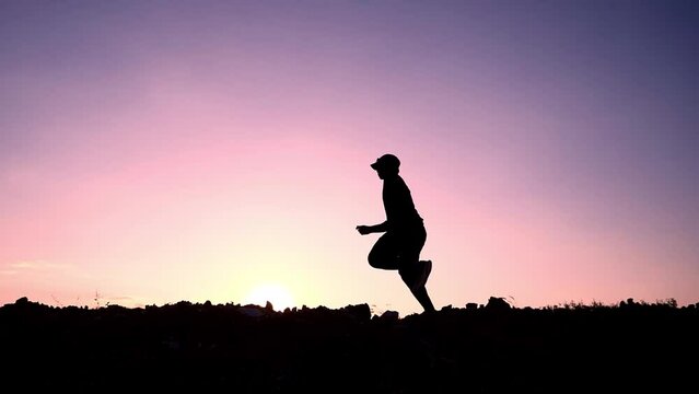 Slow motion 4x Silhouette of a man happily jogging in the evening. The concept of exercising makes you healthy.
