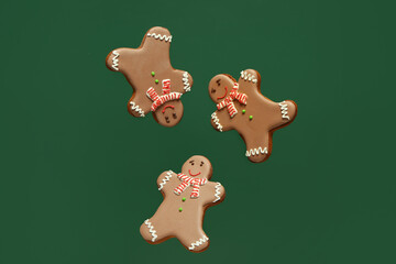 Three gingerbread cookies on green background.