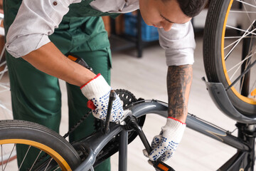 Obraz premium Young mechanic repairing bicycle in workshop, closeup