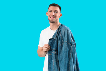 Stylish young man with denim jacket on blue background