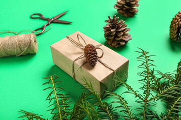 Fototapeta na wymiar Pine cones with Christmas gift box and fir branches on green background