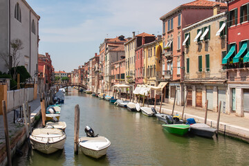 Panoramic view of a water channel in city of Venice, Veneto, Italy, Europe. Venetian architectural landmarks and old houses facades along the man made water traffic corridor. Urban tourism in summer - obrazy, fototapety, plakaty