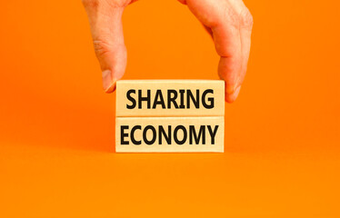 Sharing economy symbol. Concept words Sharing economy on beautiful wooden blocks. Beautiful orange table orange background. Businessman hand. Business sharing economy concept. Copy space.