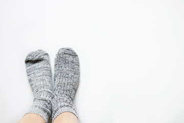 Female legs and light knitted thick warm socks on bare female legs on a white background
