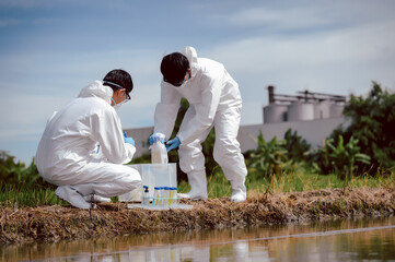 Factory scientists or biologists wear protective clothing while checking natural water sources,...