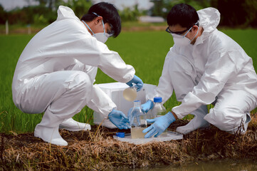 Factory scientists or biologists wear protective clothing while Collecting water samples in natural...
