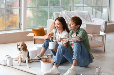 Young couple with paint can and Beagle dog during repair in their new house