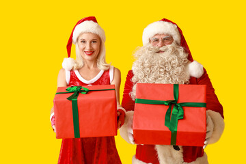 Happy Santa and MRS Claus with gift boxes on yellow background