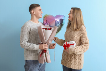 Lovely couple with bouquet of flowers and heart-shaped balloon on blue background. Valentine's Day...