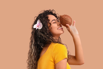 Young African-American woman with coconut on brown background