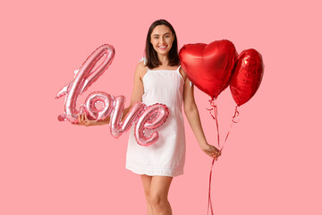 Beautiful young woman with air balloons in shape of word LOVE and heart on pink background....