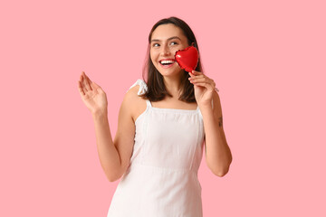 Beautiful young woman with air balloon in shape of heart on pink background. Valentine's Day celebration