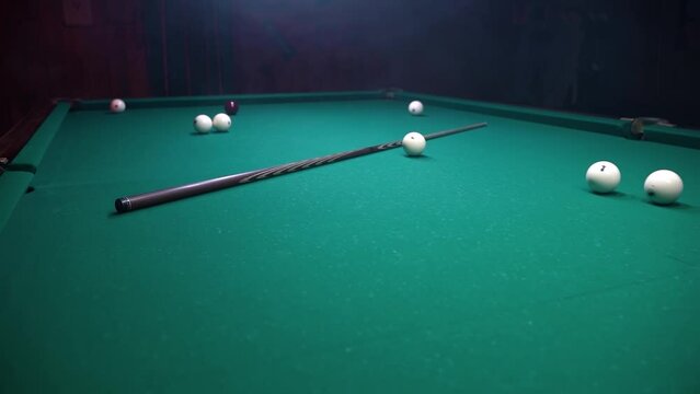 Billiards concept, balls and cue on table in pool club in atmospheric room with smoke