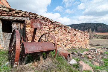 Paisaje rural de la España vaciada o despoblada con un antiguo apero de labranza abandonado. - obrazy, fototapety, plakaty
