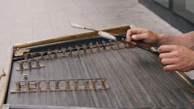A musician plays string dulcimer on the street. Close-up.