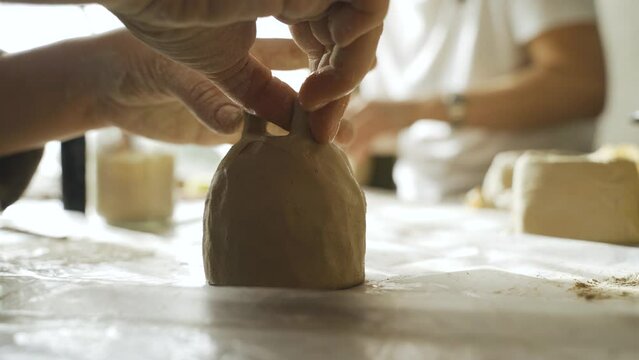 A woman makes a ceramic pot and attaches the legs. Close-up. Creative hobby.