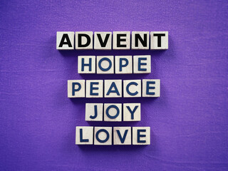 Christianity concept about Advent and Christmas season. ADVENT, HOPE, PEACE, LOVE, JOY written on wooden blocks. With blurred style background.