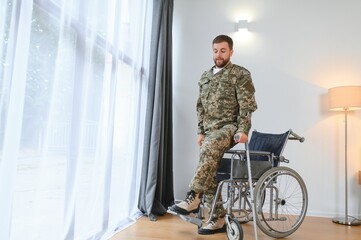 Happy soldier in military uniform getting up from wheelchair. Concept of rehabilitation of veterans