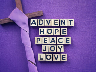 Christianity concept about Advent and Christmas season. ADVENT, HOPE, PEACE, LOVE, JOY written on wooden blocks. With blurred style background.
