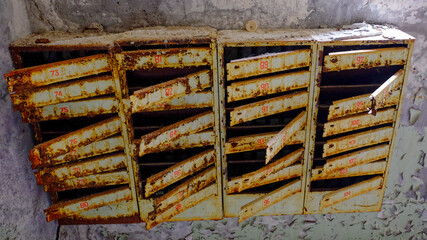 Old, rusted mailboxes with numbers painted in red.