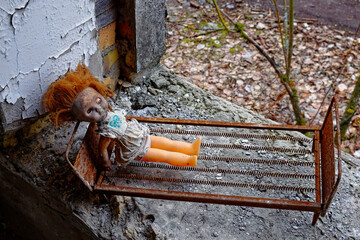 An abandoned doll in a bed, surrounded by rubble.
