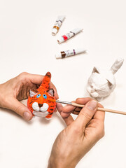 Cheerful wadding toy cats by handmade. Painting with a brush funny red cat, handmade from cotton wool. Ginger cat figurine beautiful color. Vertical view.