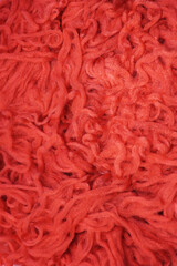 A lot of tangled thread. Red fabric background. Cords for knitting clothes, sewing factory. Soft threads for sewing. Red fluffy background. Thread for weaving.