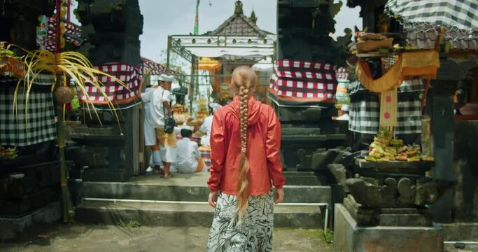 Woman in temple entrance. Tourist girl walks in Balinese shire.