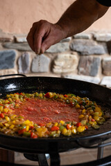 Paella from Spain recipe, throwing black pepper and fry vegetables in a big paella pan