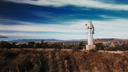 Back view of Kartlis Deda monument and Tbilisi city filmed by drone at summer day. Aerial scenery of amazing Caucasus town and picturesque nature surrounding it. Historical heritage of Georgia