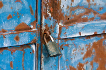 Locked security padlock on vintage rusty metal garage or storage door. No entry or no trespassing on private property concept.