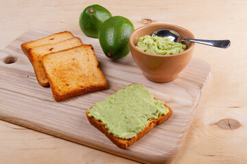 Mashed avocado toasts on light beige woden background. Concept of healthy eating and vegetarian food