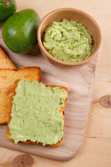 Concept of healthy eating is encapsulated in the form of avocado toast with spreading avocado paste on slice of white bread.