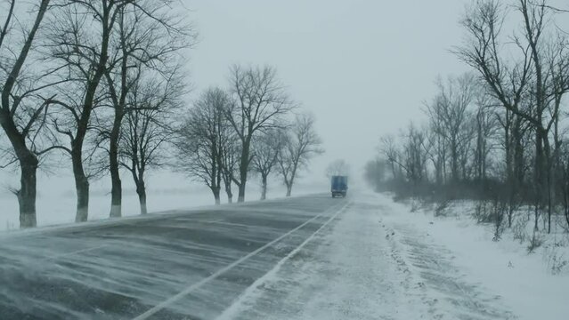 Cars moving on winter road at blizzard, 4k