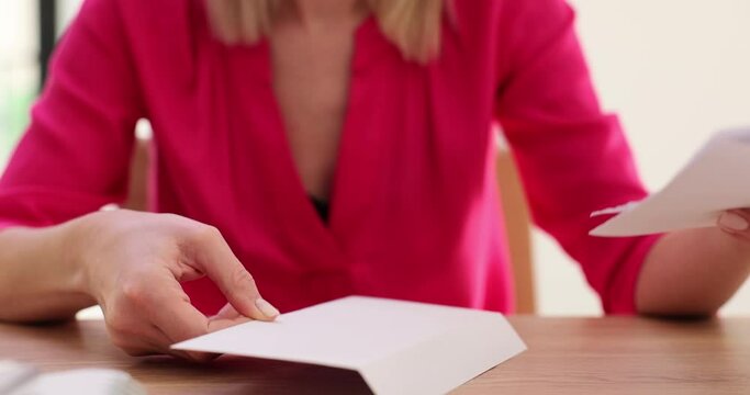 Hands of business woman receiving an open business report from envelope with documents and working at table