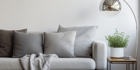 Grey lamp hanging above a couch with silver pillow in a white living room