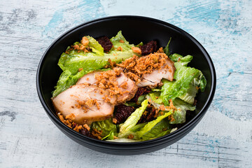 Salad with chicken fillet, sun-dried tomatoes, crispy fried onions and lettuce in a bowl.