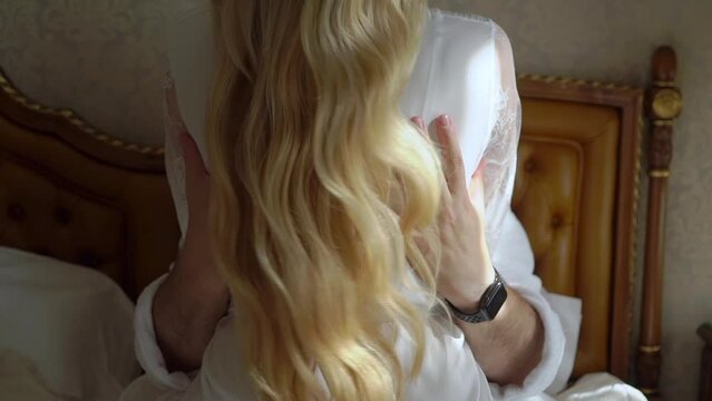 Couple in love hugging in bed. Man touch woman back. Male and female in white bathrobes. Morning in bedroom, romantic date. Bride and groom, lovers at vacation or honeymoon.