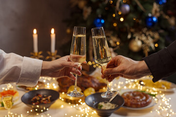 hands with glasses of champagne close-up on the background of a festive Christmas table