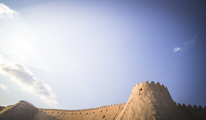 Tall ancient defensive fortifications made of bricks, clay and straw in the ancient fort city of Khiva in Khorezm, medieval architecture of the fortress at sunset