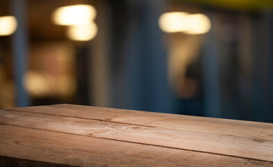 Empty wooden table top on blur light golden bokeh of cafe restaurant, bar in a dark background.