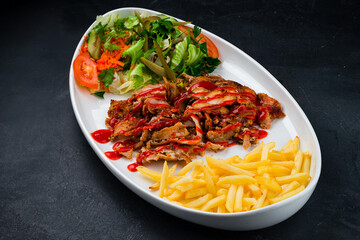 Fried meat with french fries and a salad of pickled cucumbers, tomatoes, carrots, lettuce, parsley and ketchup, shawarma.