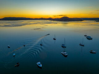 Aerial sunrise over the calm water with boats