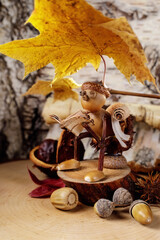 Cute small gnome made from acorns on golden autumn leaves background. Creative funny figures made...